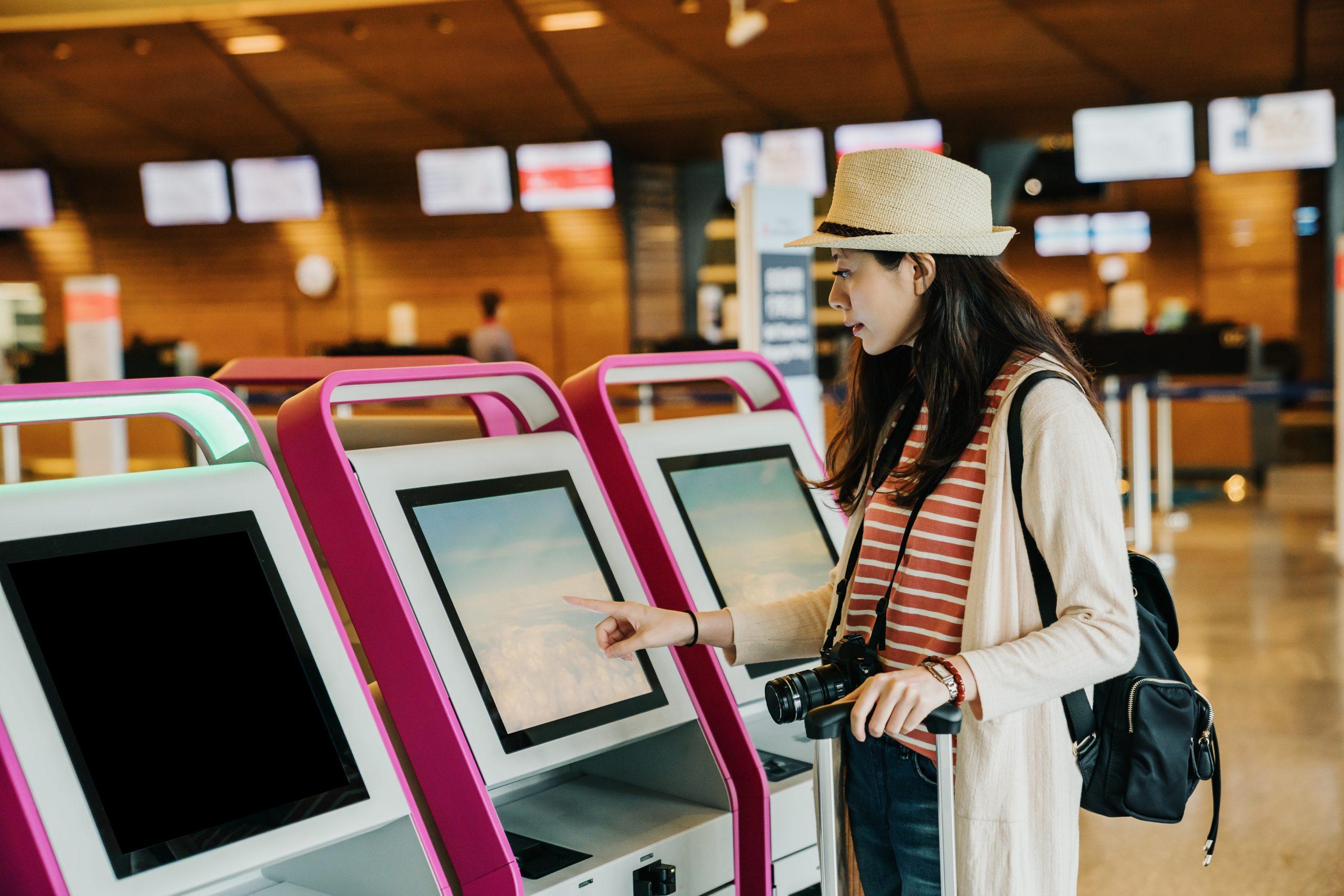 woman using self check-in kiosks in lobby